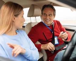 Image of driving instructor greeting a student next to a dualcontrol car