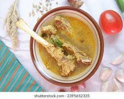 Gambar steaming bowl of Tengkleng Pak Manto, with tender goat meat and a rich, spicy broth.