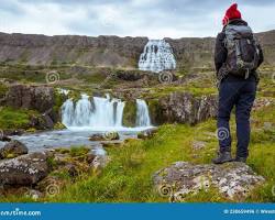 Gambar backpacker standing in front of a waterfall in Iceland