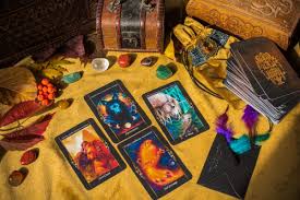 Mesa com cartas de tarot, pedras, folhas secas e caixas de madeira, sugerindo um ambiente místico e de adivinhação.