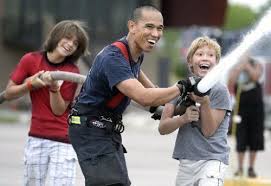 Alexei Schneeweiss Cole, 12, right, laughs while spraying a fire hose with Boulder Fire Rescue firefighter David Garcia and Lalo Jimenez Silva, 11, ... - 20130805__06dcafirw~1_500