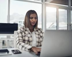 Image of person working on a laptop, focused and writing