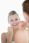 Woman using <b>dental floss</b> in front of mirror - depositphotos_23487949-Woman-using-dental-floss-in-front-of-mirror