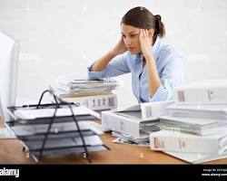 Image of person looking stressed while surrounded by paperwork