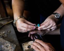 Hands of a Cambodian artisan carefully crafting a piece of silver jewelry.