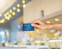 credit card reader on a cafe counter with a blurred hand giving a cardの画像