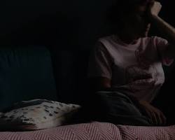 صورة person sitting alone in a dark room with their head in their hands