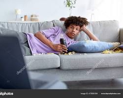 Image of someone relaxing on a couch with a laptop and snacks