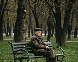 Image of elderly person sitting alone on a park bench in Europe