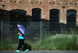 Pedestrian walking under an umbrella during an extreme Southern California heat wave