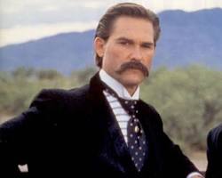 Image of Wyatt Earp, a sternfaced lawman with a mustache and a determined expression, wearing a cowboy hat and holding a revolver