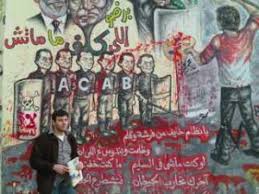 War Resister staff person Ali Issa in front of a mural stating, in part: “Oh regime which is scared of a paintbrush and a pen. You oppress us … - Ali-in-Egypt-300x225