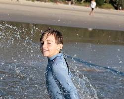 child playing in shallow water with a marine shoe onの画像