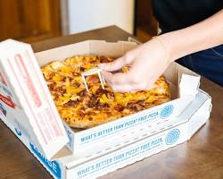 Image of someone wearing a gas mask while eating a slice of pizza