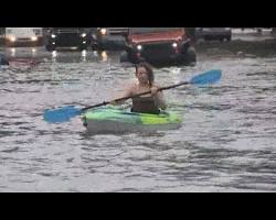 Image of people paddling down a flooded street