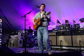John Mayer performing on stage with guitar