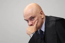 Alexandre de Moraes, ministro do STF, com a mão no rosto, em pose pensativa.