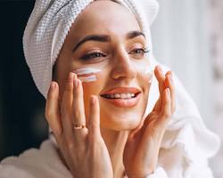 صورة woman applying sunscreen on face
