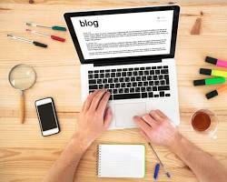 person writing a blog post on a laptop resmi