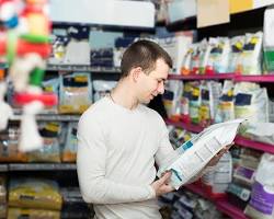person reading the ingredients on a pet food packageの画像