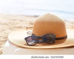 summer hat and sunglasses on sandの画像