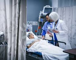 Image of patient in a hospital bed holding their side in pain