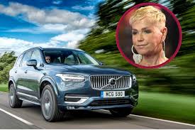 Xuxa Meneghel em um Volvo XC90 em movimento em uma estrada arborizada, com um círculo vermelho mostrando seu rosto.