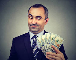 Image of someone holding a stack of money with a sly grin