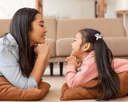 Japanese mother and two teenage daughters smiling together in a warm living room, emotional connection, peaceful atmosphereの画像