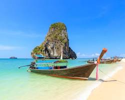 Image of Thai longtail boat on a turquoise beach with limestone cliffs