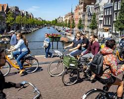 Image of people walking or cycling along the canals in Amsterdam