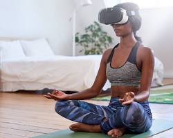 Image of person wearing VR headset meditating on a beach