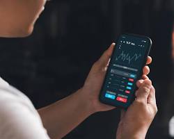 Image of person using a smartphone to invest in a stock market app