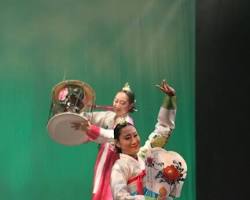 diverse audience watching a Korean traditional music and dance performance, showing people of different ethnicities enjoying the show 이미지