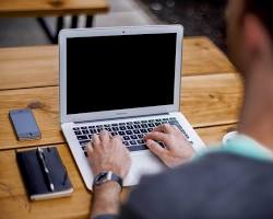 Image of student coding on a laptop with a smartphone mockup