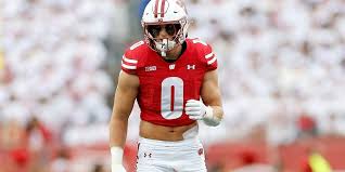 Football player in red jersey number 0 standing on field