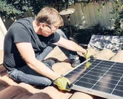 Image of person wearing safety gear while cleaning solar panels