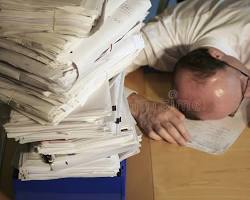 Image of someone looking overwhelmed surrounded by tax forms