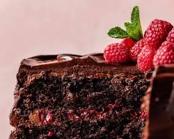 slice of fudgy chocolate cake with chocolate ganache frosting and fresh raspberries